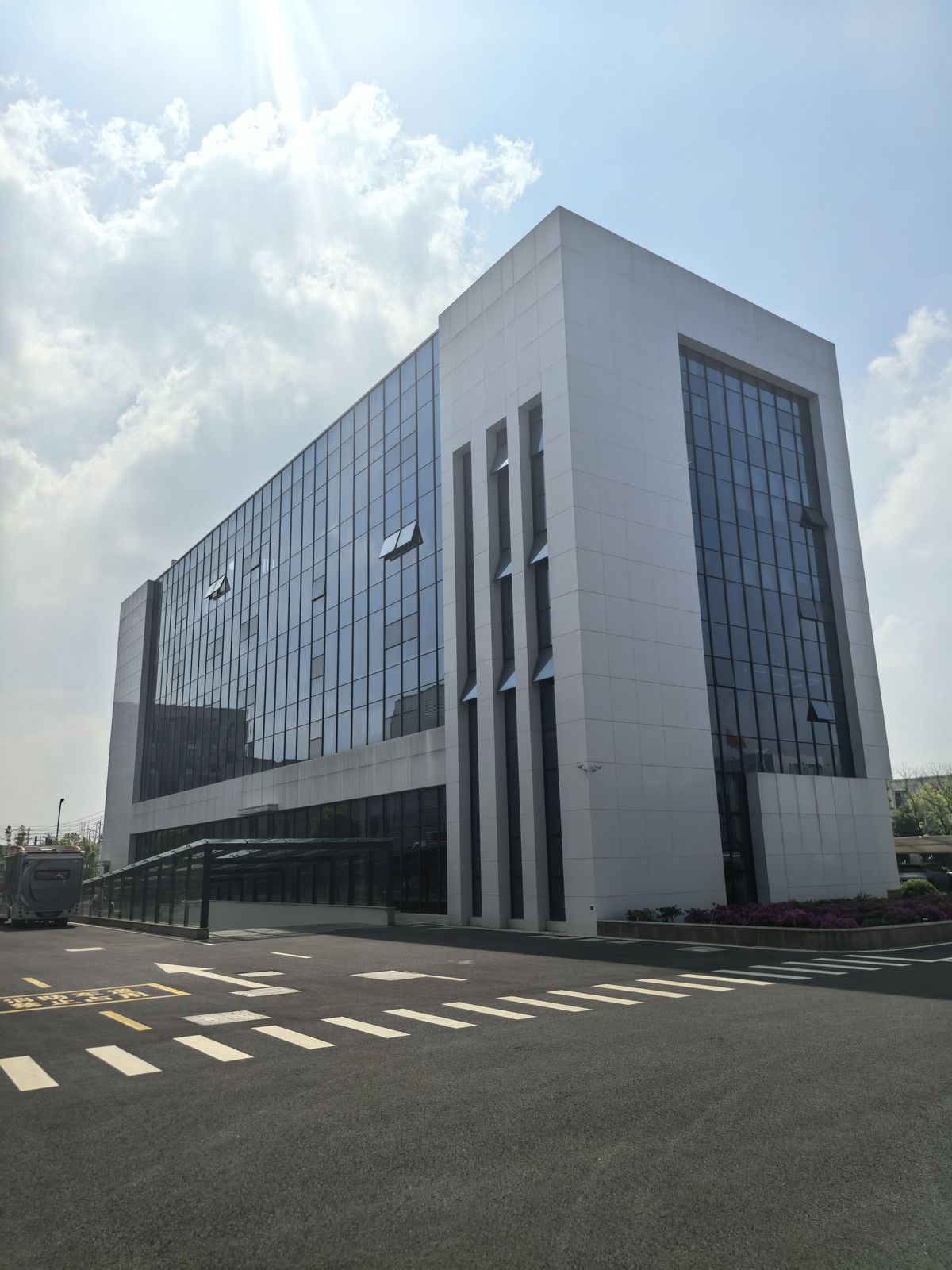 Fachada do prédio administrativo, com estrutura envidraçada e revestimento branco